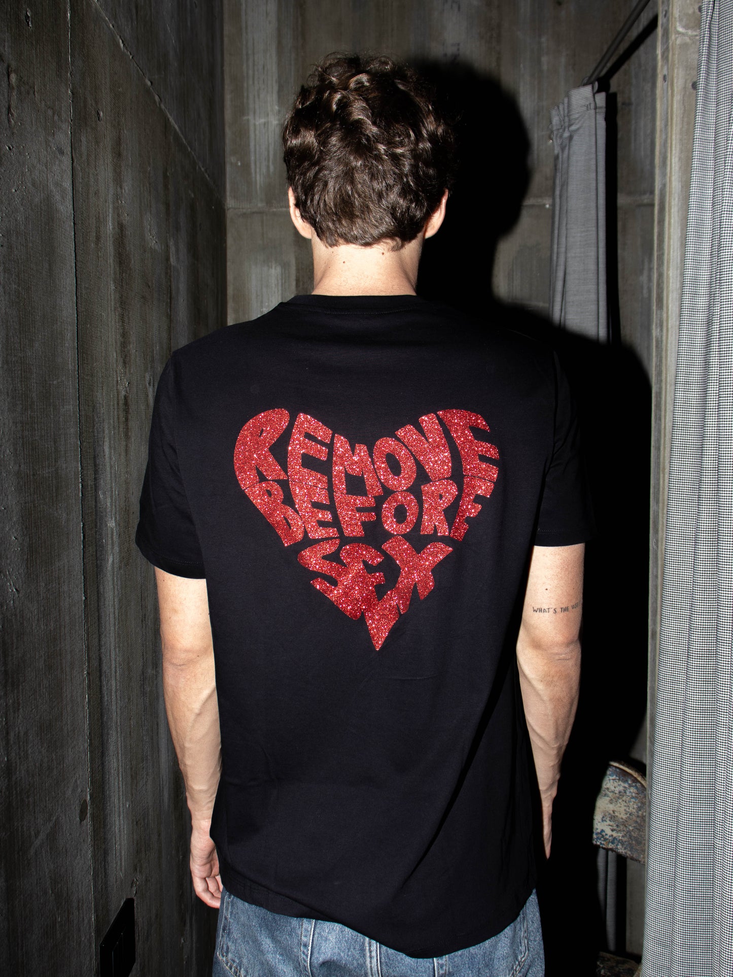 Unisex black T-shirt with 'Remove Before Sex' in red glitter on the back, made in Italy from 100% cotton. Street wear style.