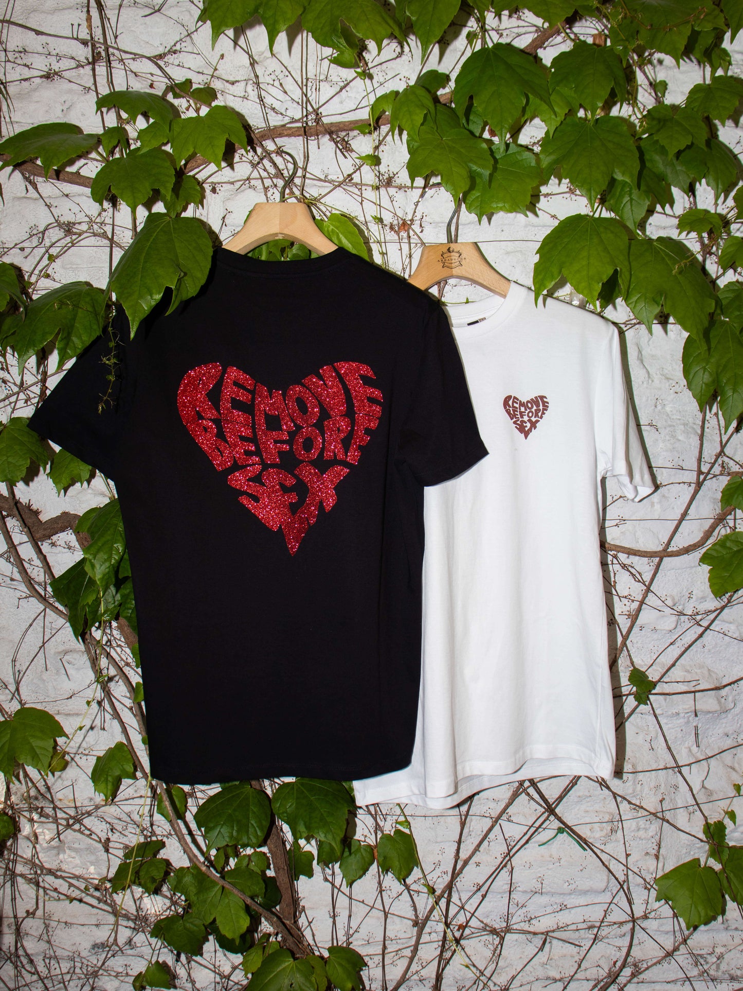 Unisex streetwear T-shirts: black with glitter 'Remove Before Sex' logo and white with heart logo, made in Italy, 100% cotton.